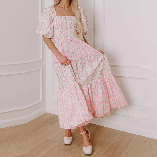 Woman wearing a pink floral dress in a minimalistic room.