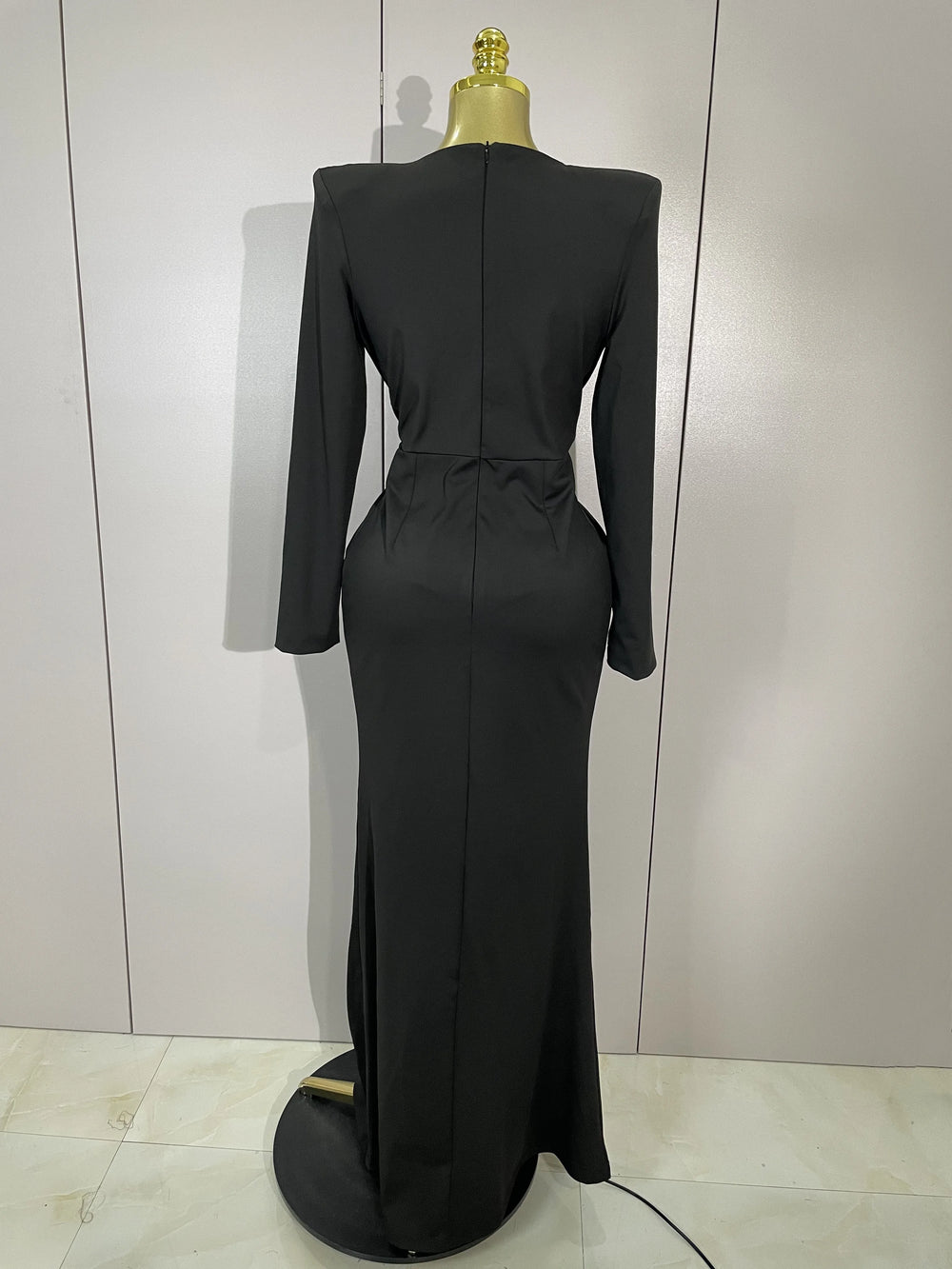 Black evening gown on a mannequin against a plain background