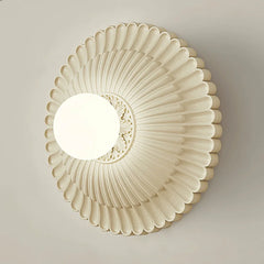 A round French retro wall sconce with a milk white glass lampshade, casting a soft glow on a bedside table. A