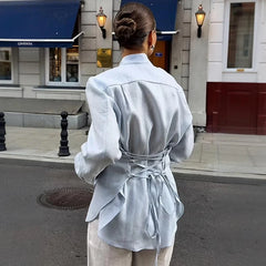 Person wearing a light blue outfit walking on a city street.