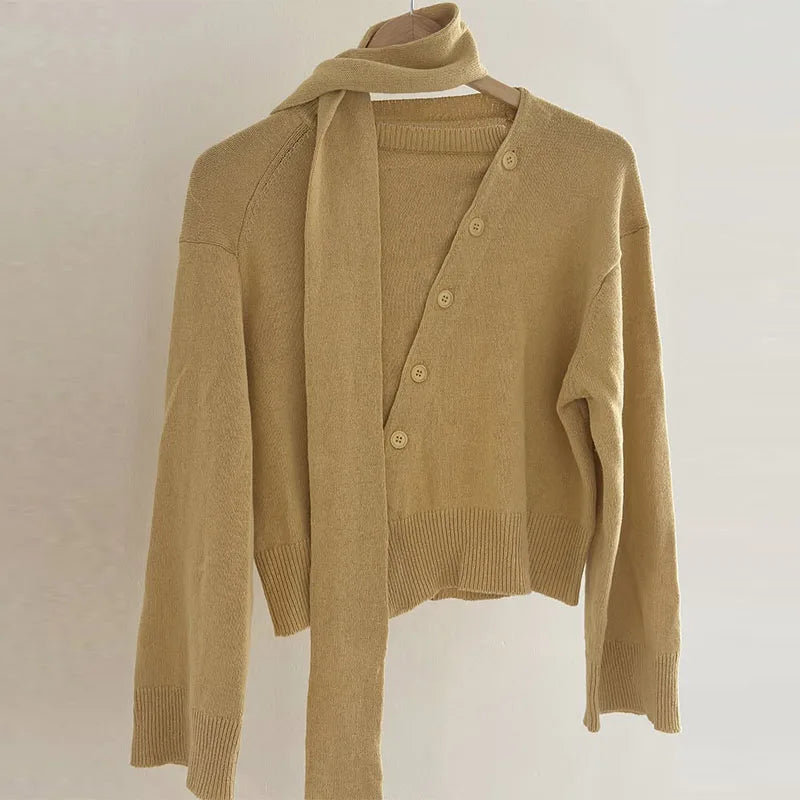 Beige cardigan on a hanger against a plain background