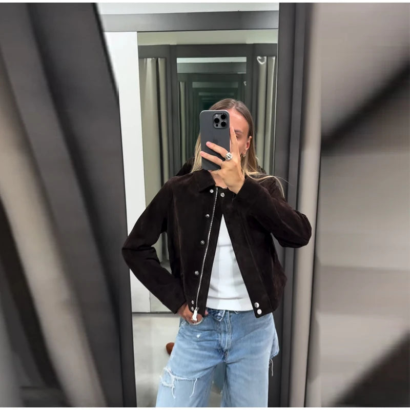 Person taking a mirror selfie wearing a black jacket and blue jeans.