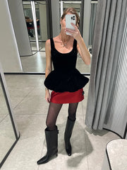 Person wearing a black top and red skirt with black boots in a mirror selfie.