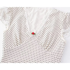 White blouse with black polka dots and lace details on a white background
