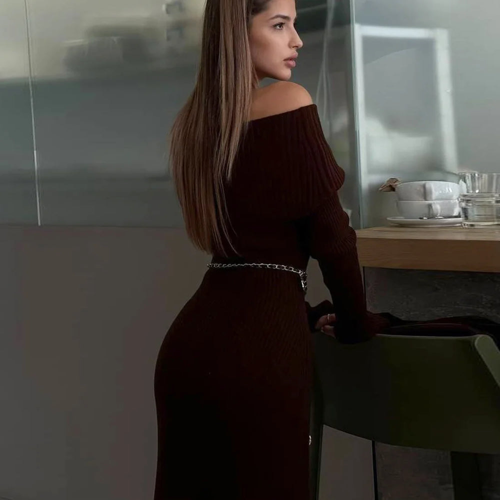 Woman in a dark brown off-shoulder dress standing in a modern kitchen.