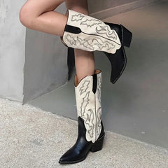 Person wearing black and white cowboy boots against a neutral background