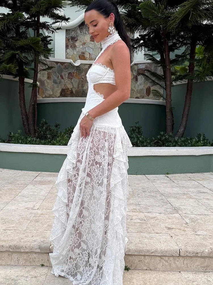 Woman in a white lace dress standing on steps with greenery in the background