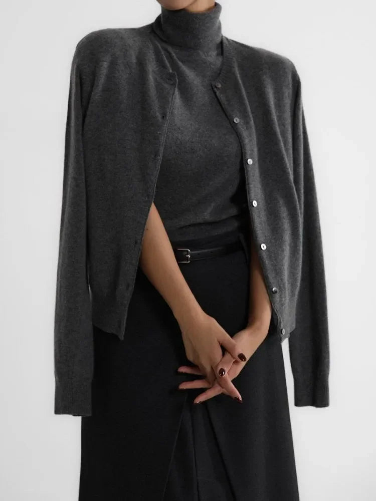 Person wearing a dark gray cardigan over a black turtleneck and skirt