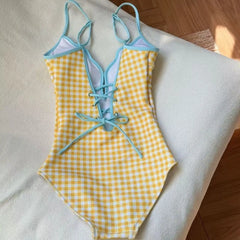 Back view of yellow gingham print one-piece swimsuit with blue cover-up skirt