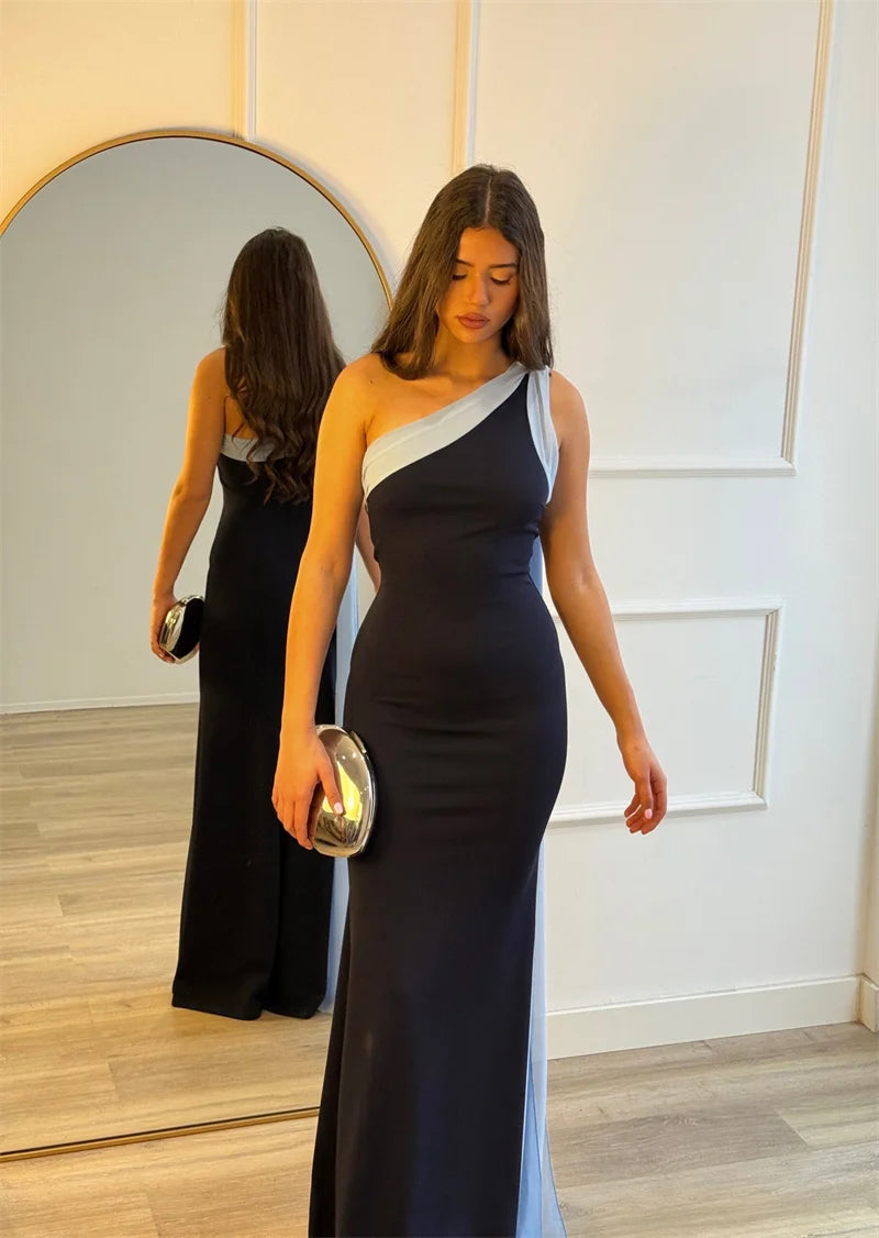 Woman in a black and white dress standing in front of a mirror.