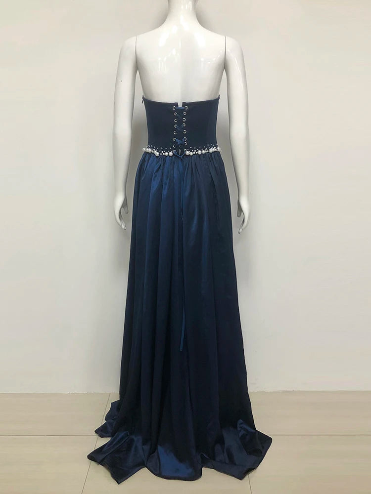 Navy blue evening gown with beaded waist on a mannequin against a white background