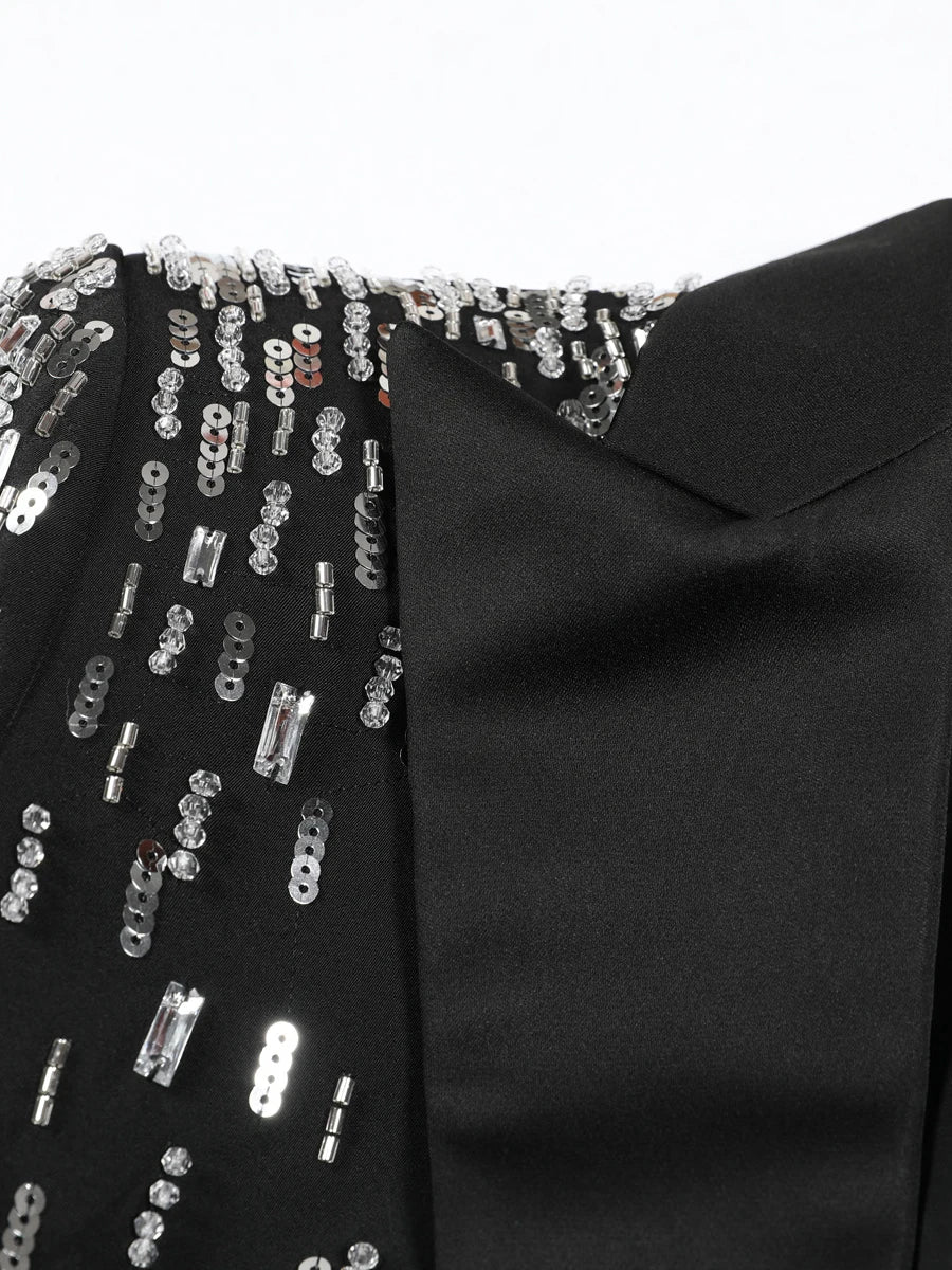Black garment with silver sequin embellishments on a white background