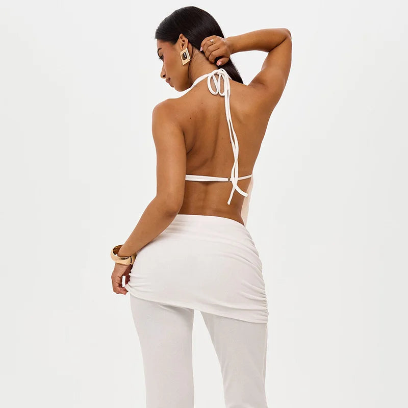 Woman wearing a white halter top and pants on a light gray background