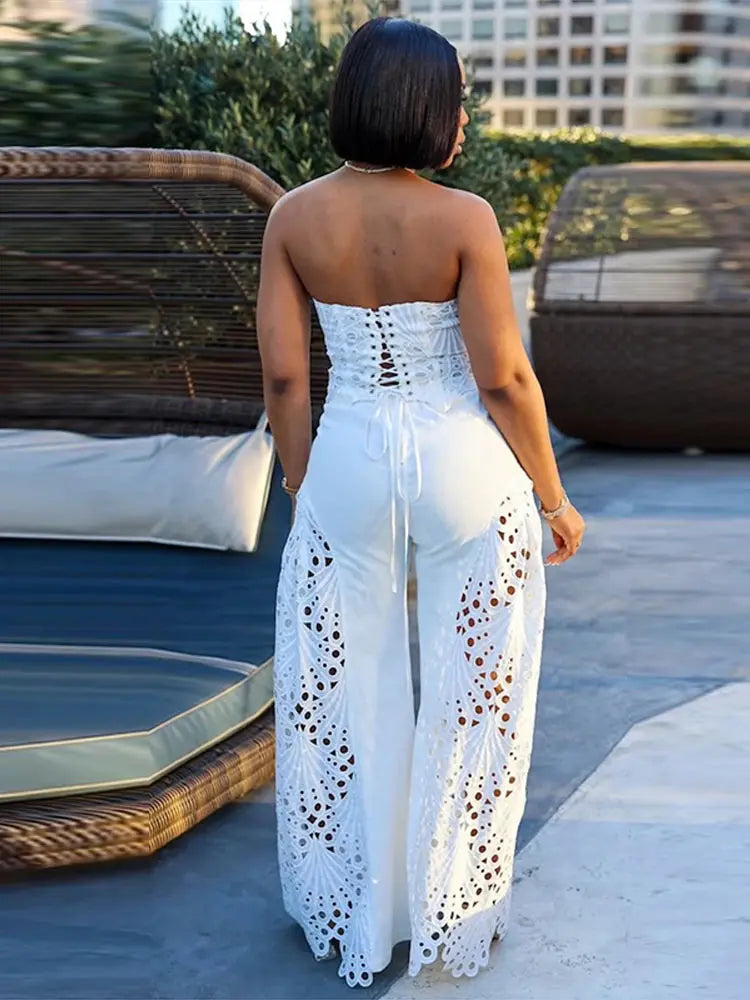Woman wearing a white strapless jumpsuit with cut-out details, standing outdoors.