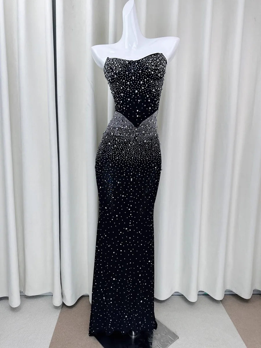 Black evening gown with silver sequins on a mannequin against a white curtain background