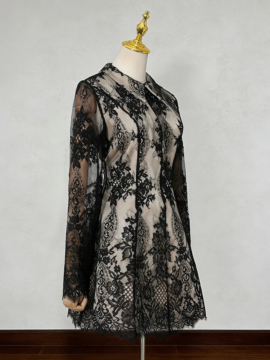 Black lace dress on a mannequin against a plain background