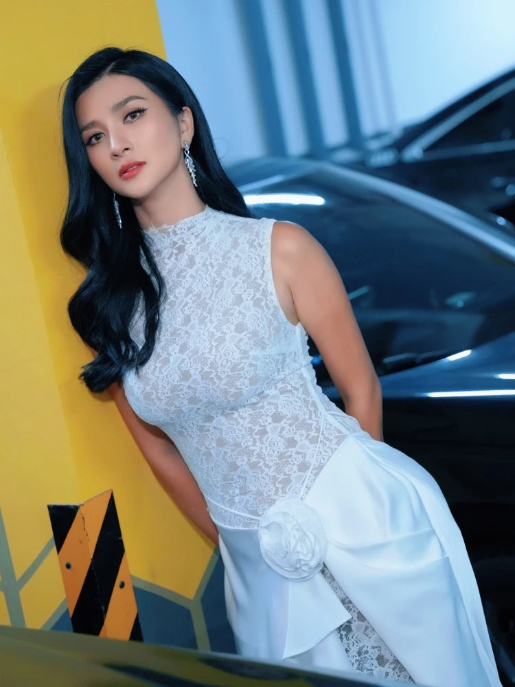 Woman in a white dress standing next to a car with a yellow wall in the background