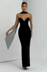Woman wearing a black strapless gown with sheer sleeves against a white background