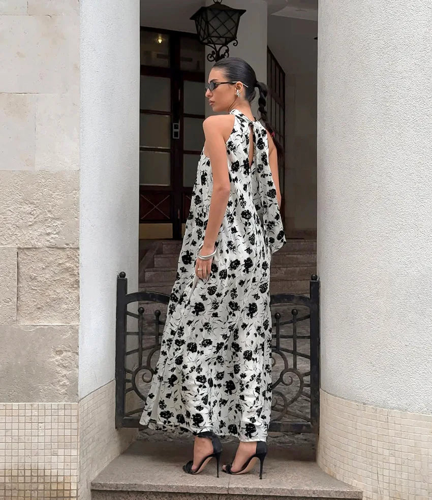 Woman in a black and white floral dress standing in an outdoor setting.