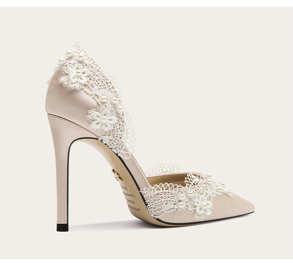 Beige high-heeled shoe with white lace detailing on a light beige background