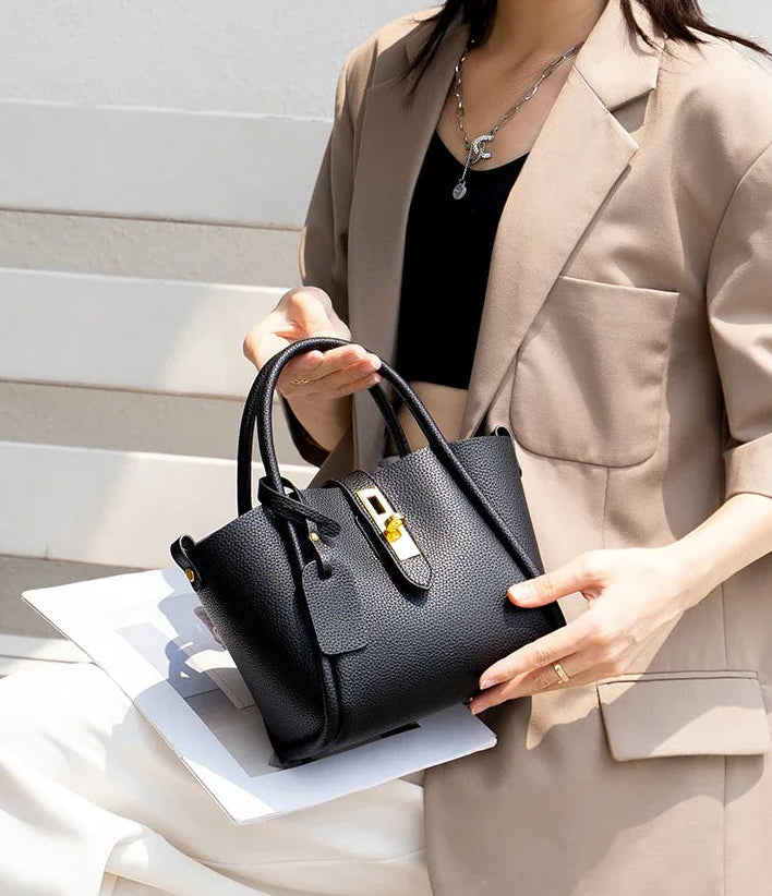 Person holding a black handbag with a neutral background