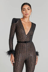 Woman wearing a black lace jumpsuit with feathered sleeves on a gray background