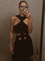Person wearing a black dress with cut-out design in front of a textured wall.