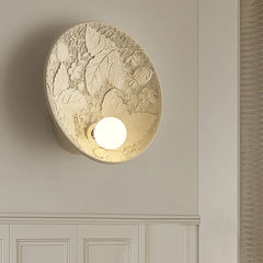 A round French wall sconce with a milk white glass lampshade, casting a soft glow in a cozy bedroom. B