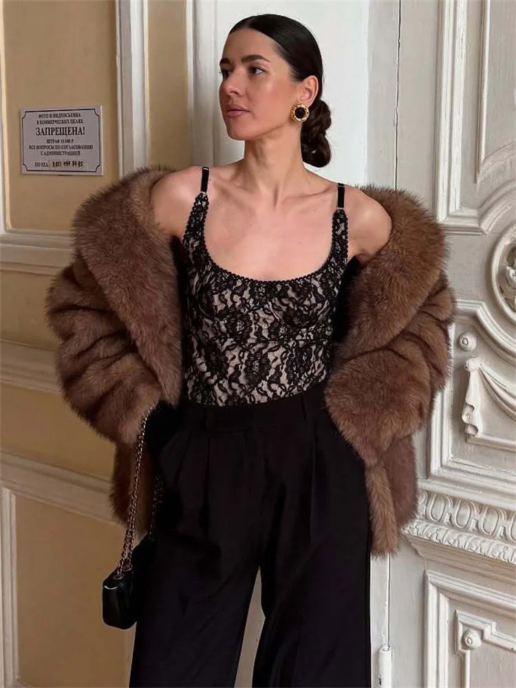 Woman wearing a brown fur coat and black floral top in an elegant interior setting.
