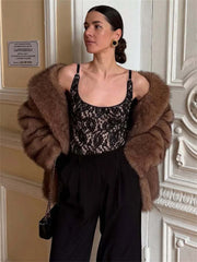 Woman wearing a brown fur coat and black floral top in an elegant interior setting.