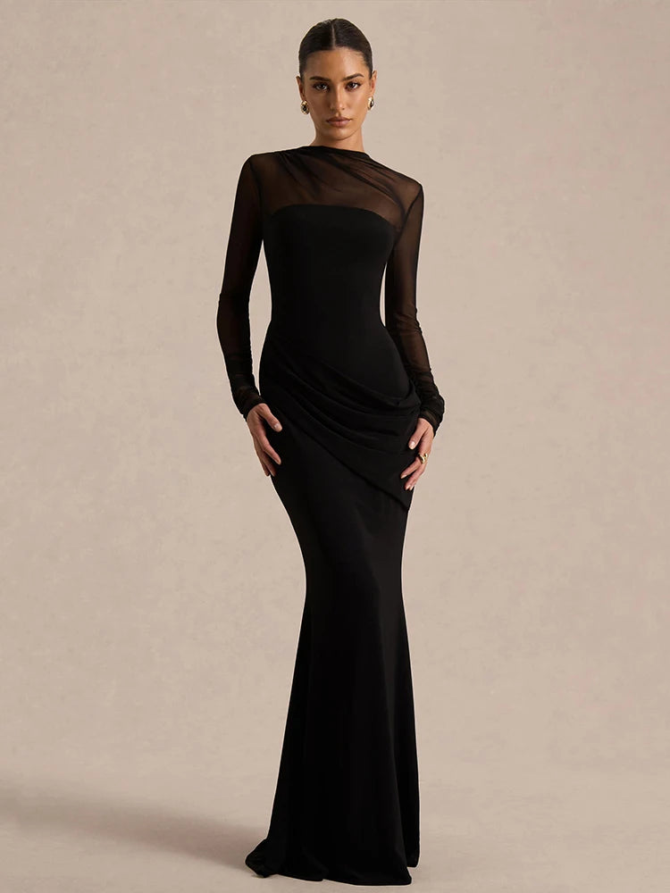 Woman wearing a black evening gown with sheer sleeves against a beige background