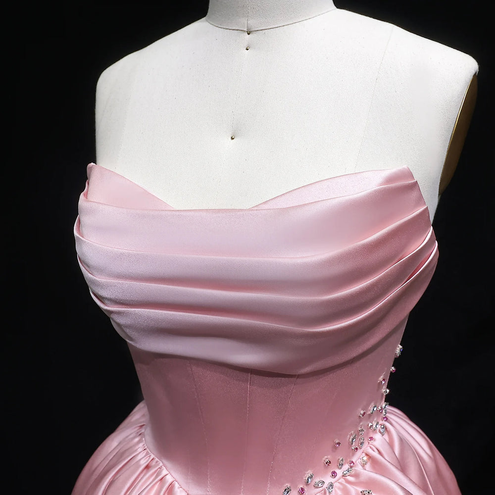 Pink evening gown on a mannequin against a black background