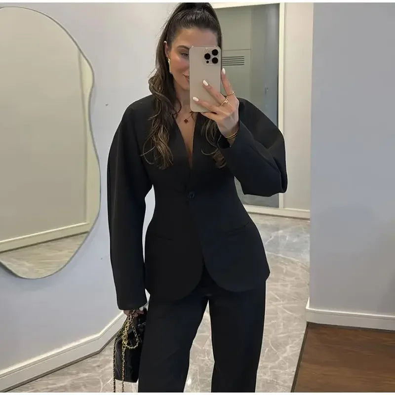 Person wearing a black suit taking a mirror selfie in an indoor setting.