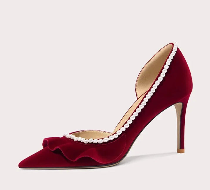 Red high-heeled shoe with pearl details on a light gray background