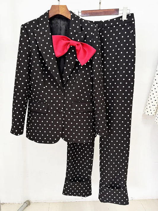Black polka dot print blazer and trousers with a red bow detail on a hanger.