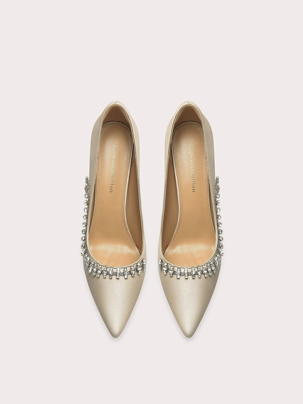 Pair of gold high-heeled shoes with crystal embellishments on a light gray background