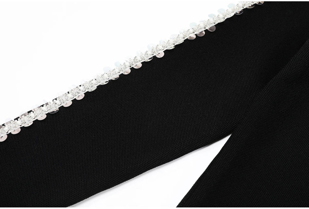 Close-up of the embellished trim along the side seam of black knit trousers.