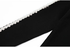 Close-up of the embellished trim along the side seam of black knit trousers.