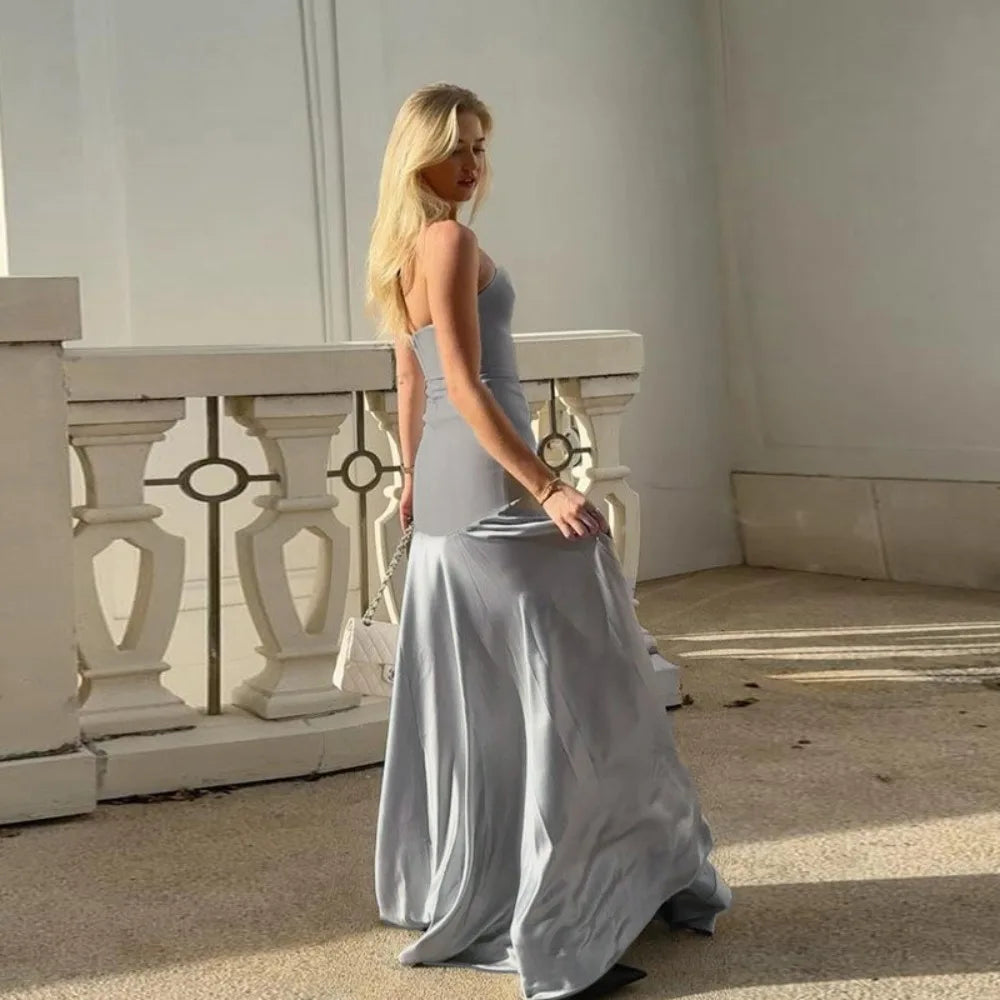 Woman in a long, light-colored dress standing on a balcony.