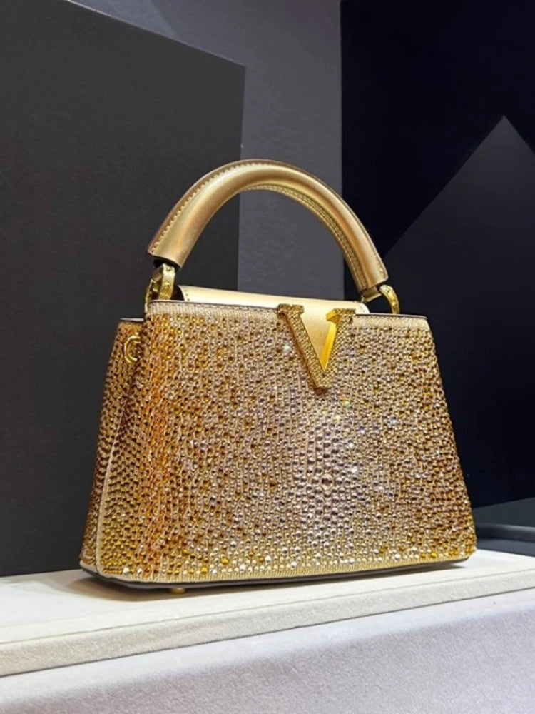 Gold crystal embellished structured bag with top handle.