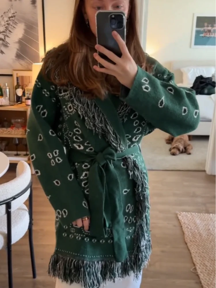 Person wearing a green patterned cardigan in a home setting