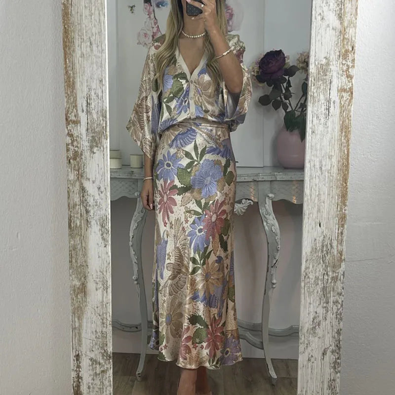 Woman taking a mirror selfie wearing a floral dress in a room with a distressed wooden frame.