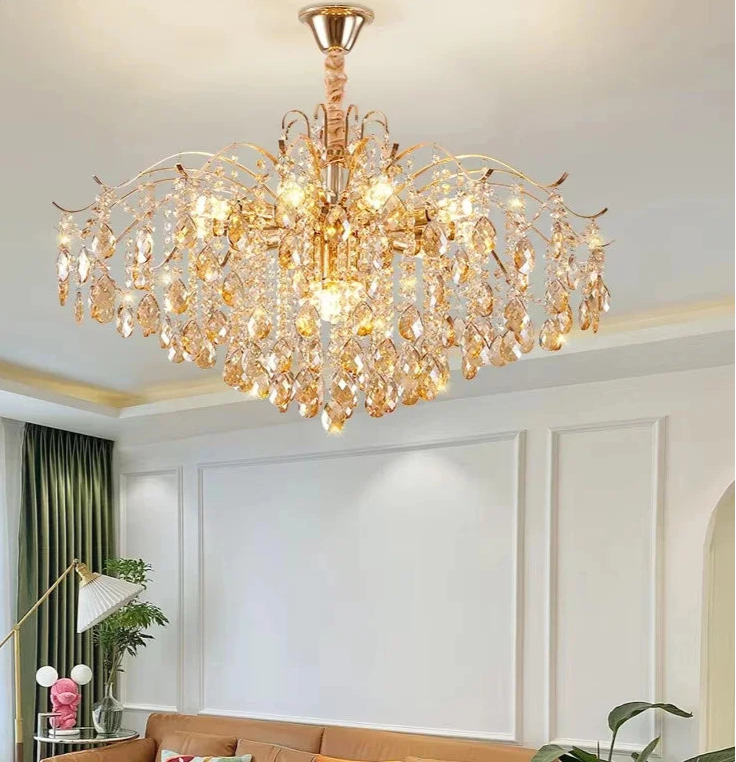 Gold chandelier hanging in a room with a couch and decorative items.