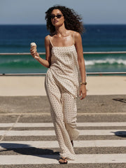 Woman in a polka dot dress holding an ice cream by the ocean.