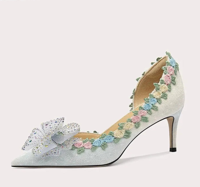 High-heeled shoe with floral embroidery and a bow on a white background