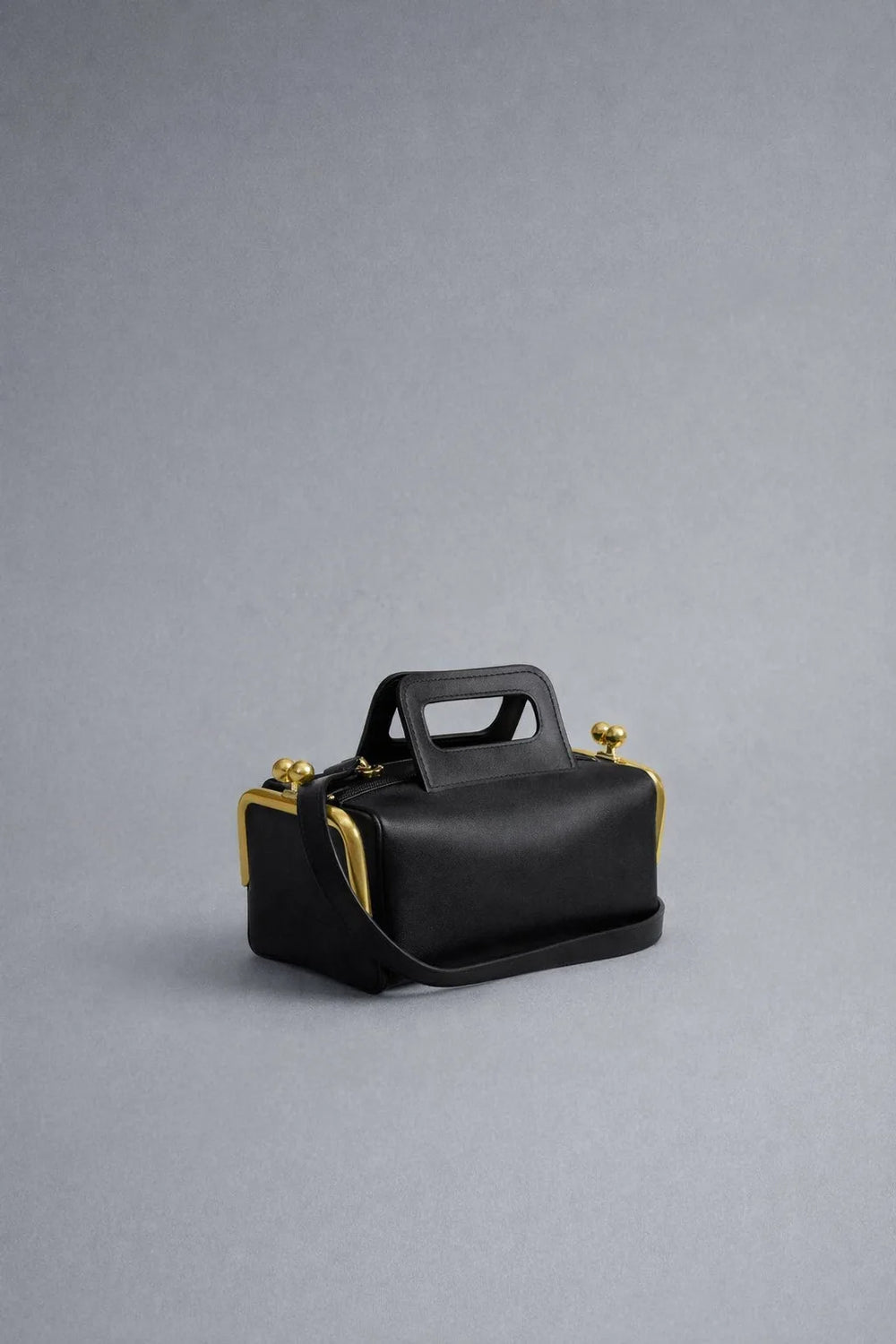 Black handbag with gold accents on a gray background