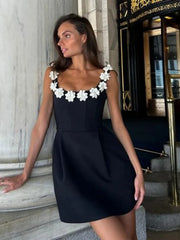 Woman wearing a black dress with white floral embellishments standing on steps.