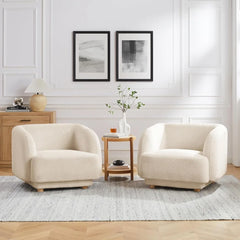 Two beige armchairs in a living room with a side table and framed pictures on the wall.
