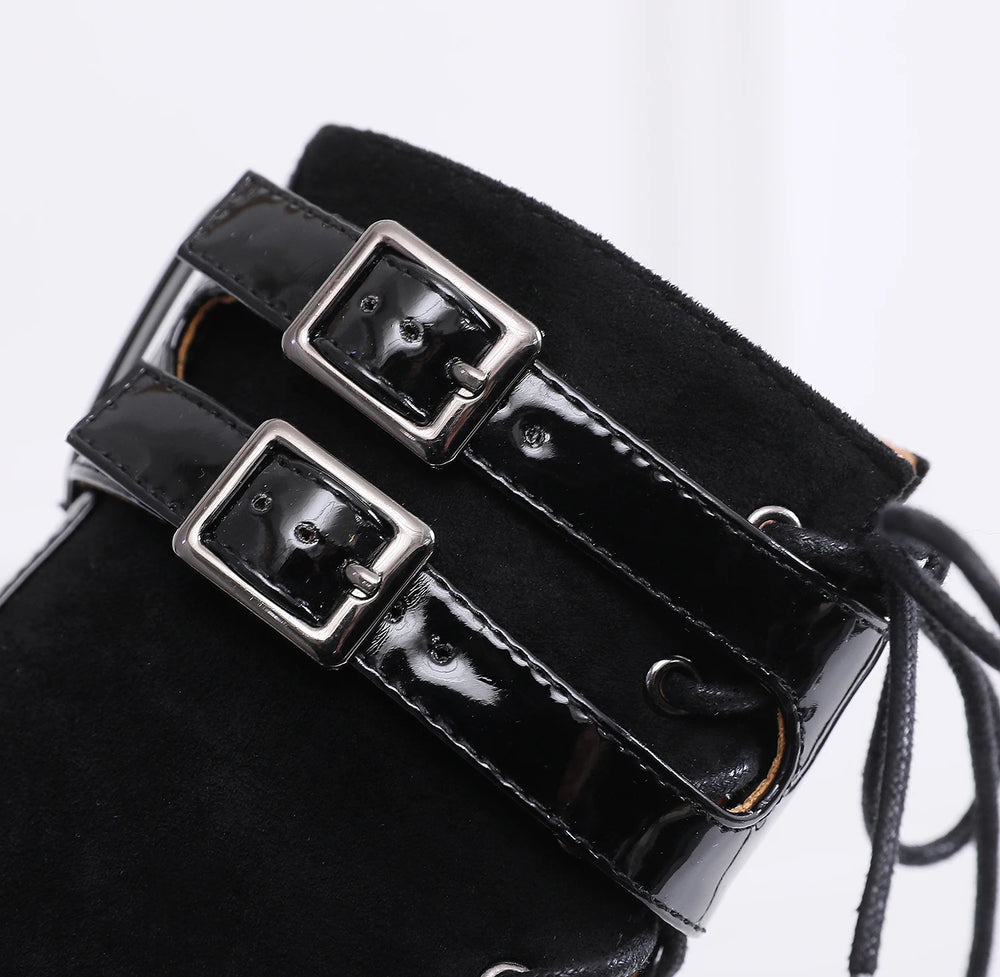 Black patent leather boot with decorative buckles on a white background