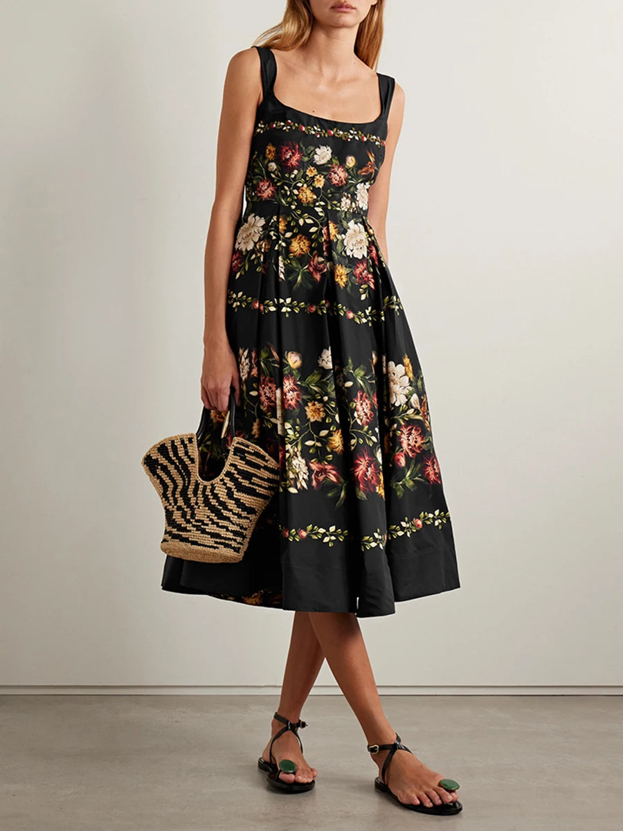 Black floral print square neck sleeveless A-line midi dress with a gathered hem worn by a model holding a woven bag.